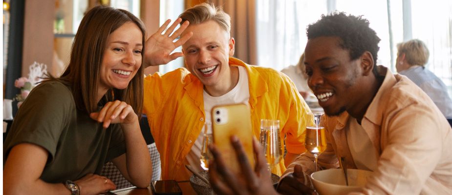 Grupo de amigos foodie lovers haciédose una foto en un restaurante para subirla a redes sociales.